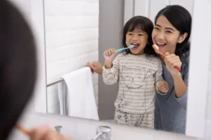 Mother and child brushing teeth together